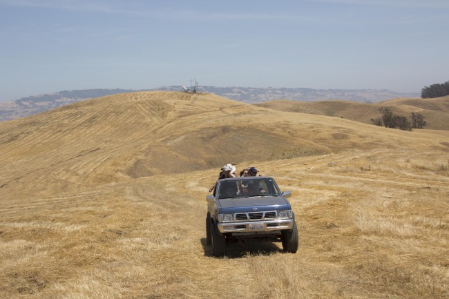 group of people riding a pickup in the open fields of farm