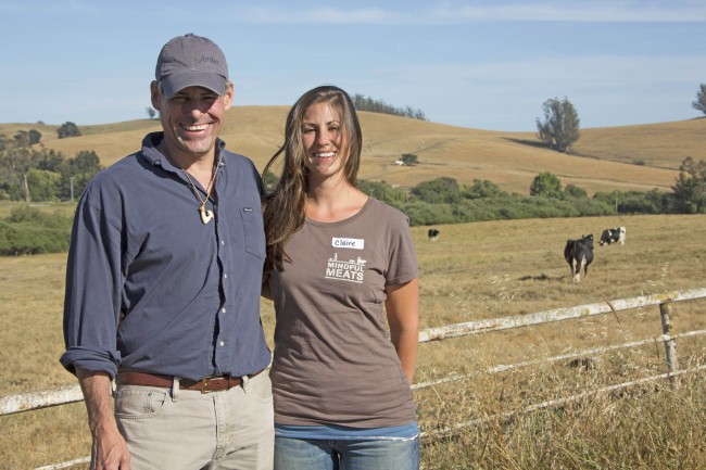 a couple with a background of cows in the farm