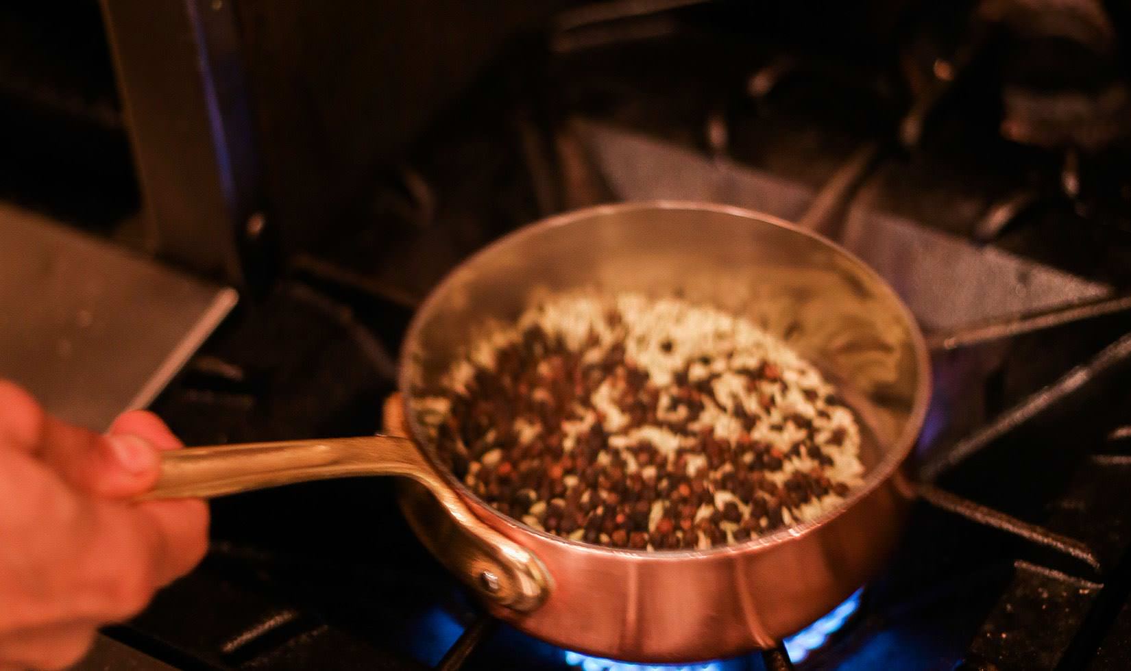 Herb Roasted Pork Belly Porchetta Recipe a person stir-frying the spices for porchetta recipe