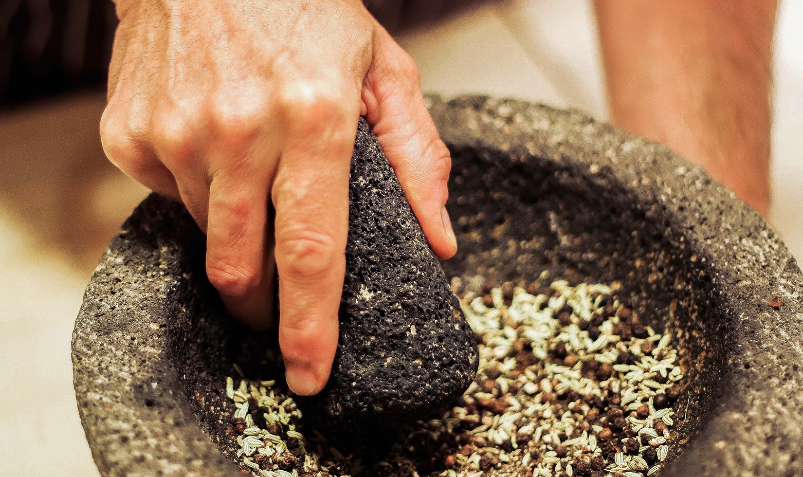Herb Roasted Pork Belly Porchetta Recipe person smashing the pepper to make it more powdery