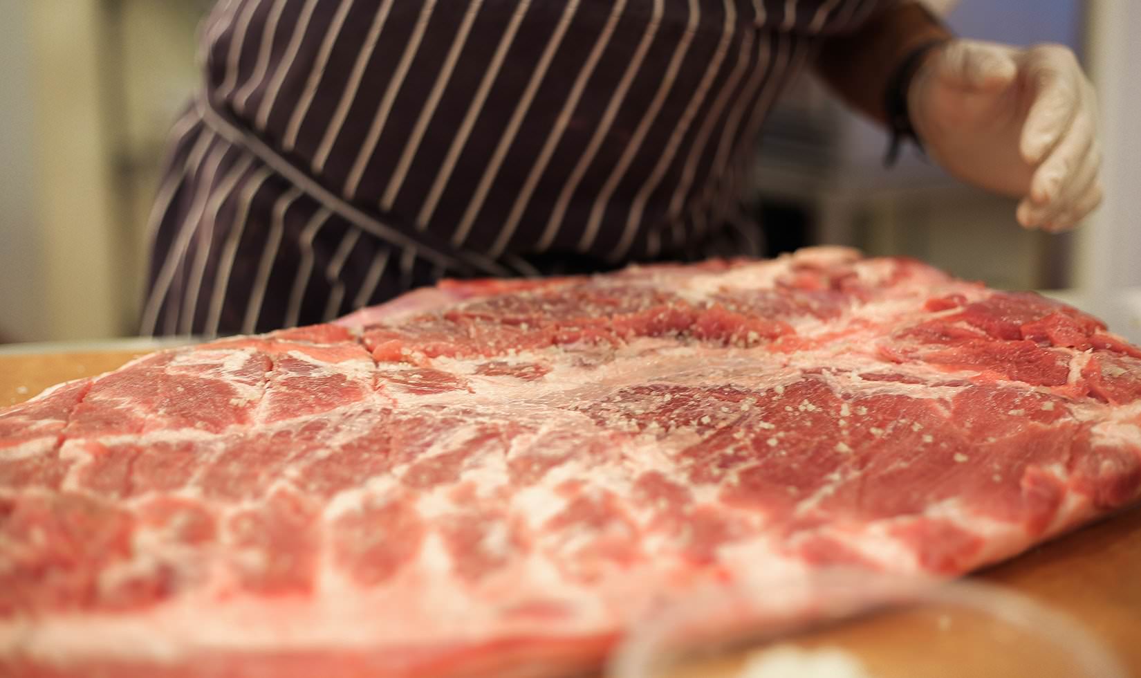 Herb Roasted Pork Belly Porchetta Recipe chef sprinkling pepper and salt in the pork belly