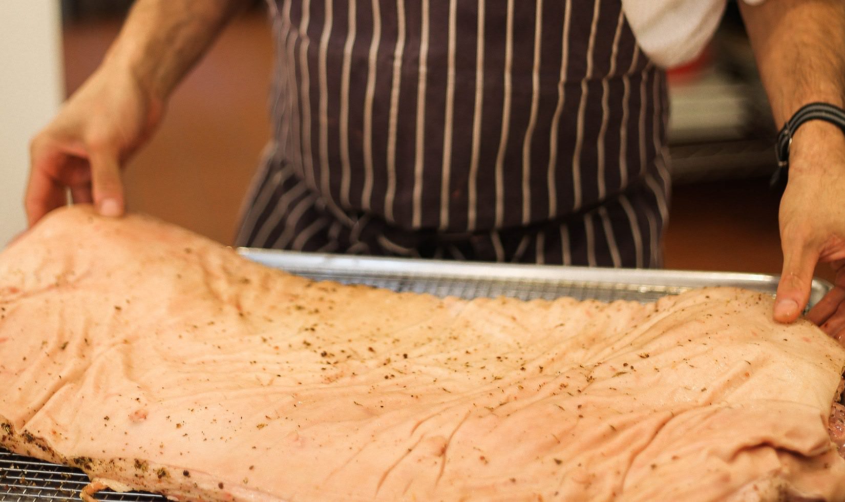 Herb Roasted Pork Belly Porchetta Recipe ready to cook pork belly with a man holding it