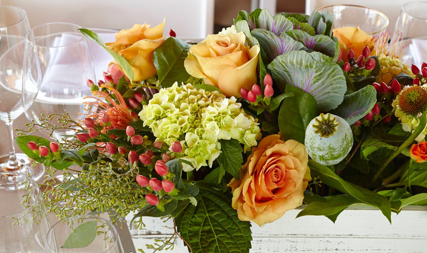 A floral arrangement with ornamental cabbage, smooth hydrangea, orange spray roses and orange flame calla lily.