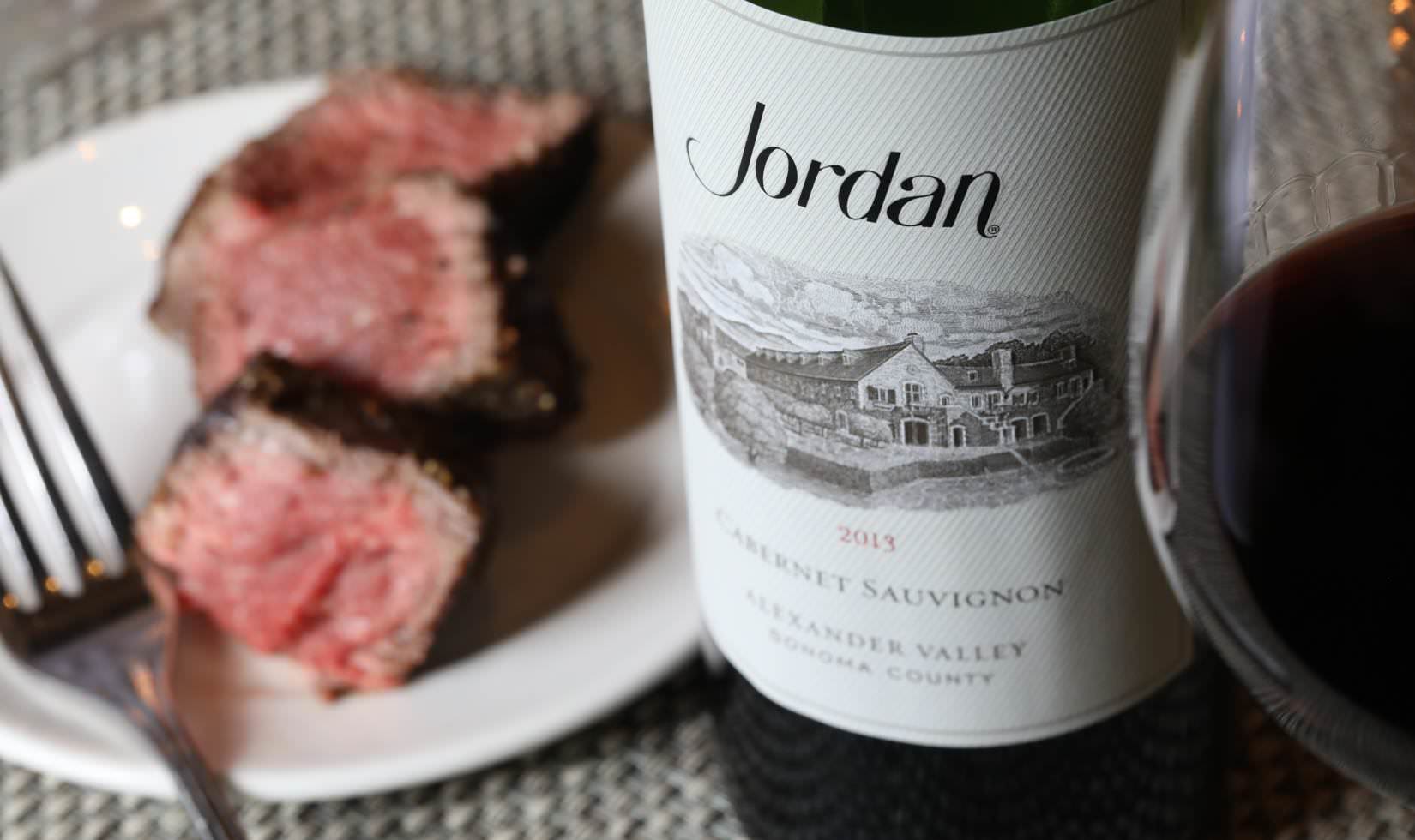 sliced steak on a plate next to a bottle of Jordan Winery 2013 Cabernet