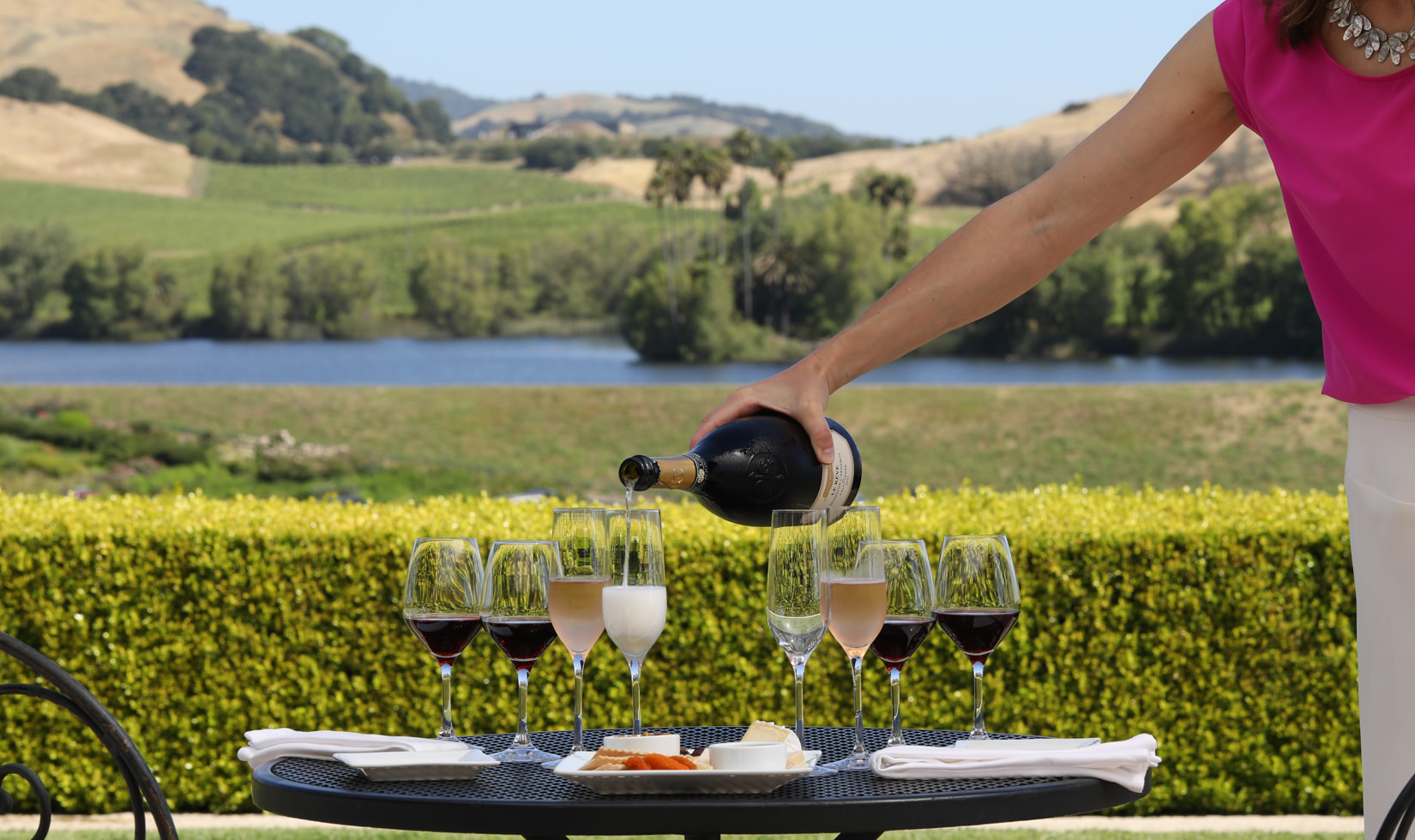 Pouring wine at a table setting for wine and cheese tasting on the terrace at Domaine Carneros terrace Napa