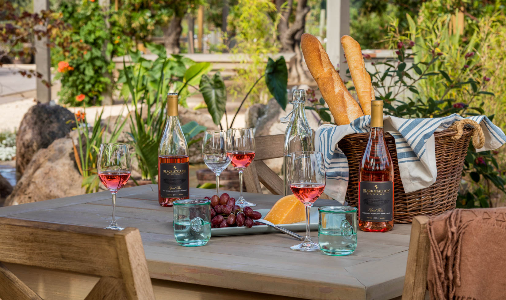 Napa Wine and Cheese Tasting WIneries 3 red wine bottles with 4 wine glasses in a table with red grapes and bread