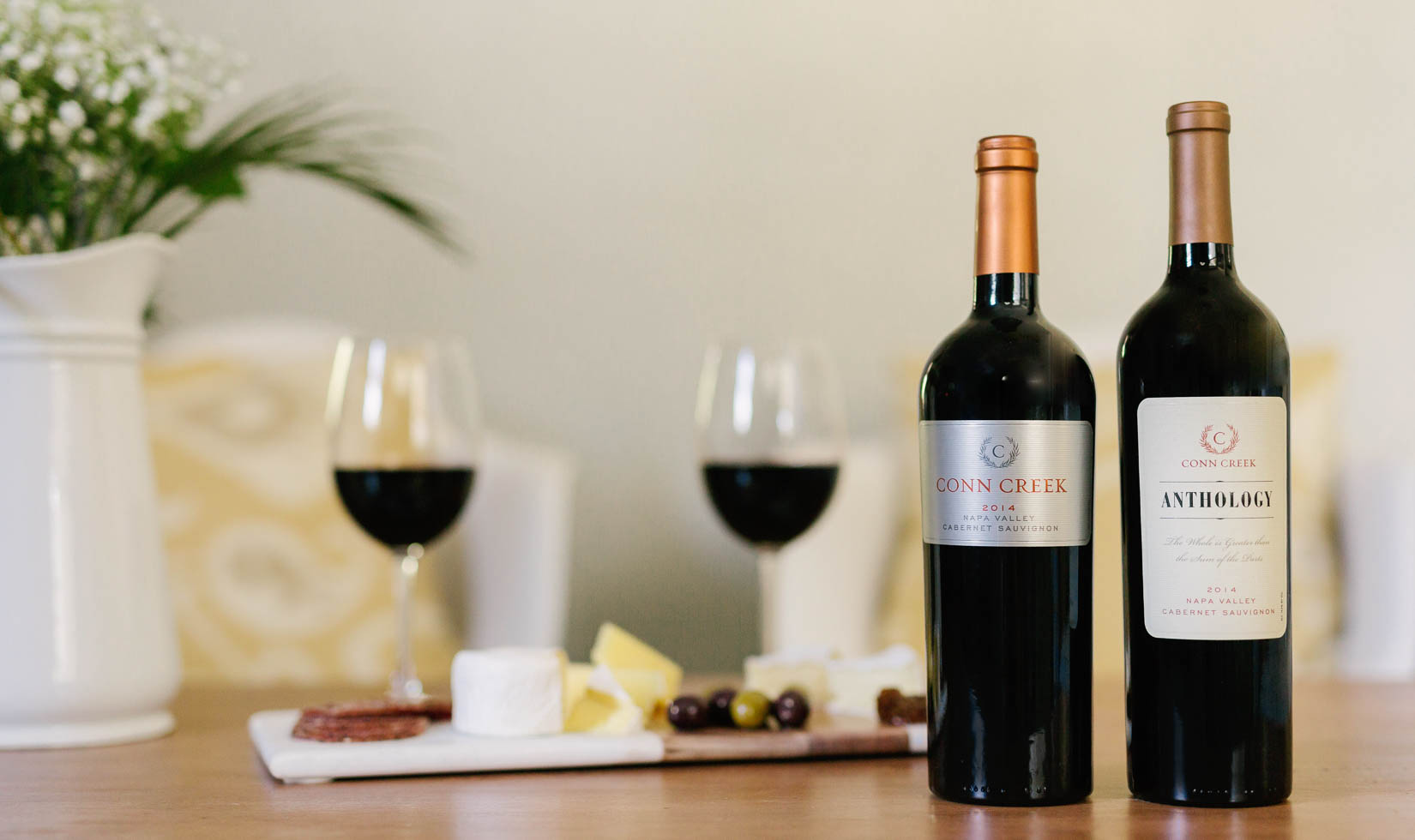 2 bottles of wine with a background of 2 wine glasses with food pairing