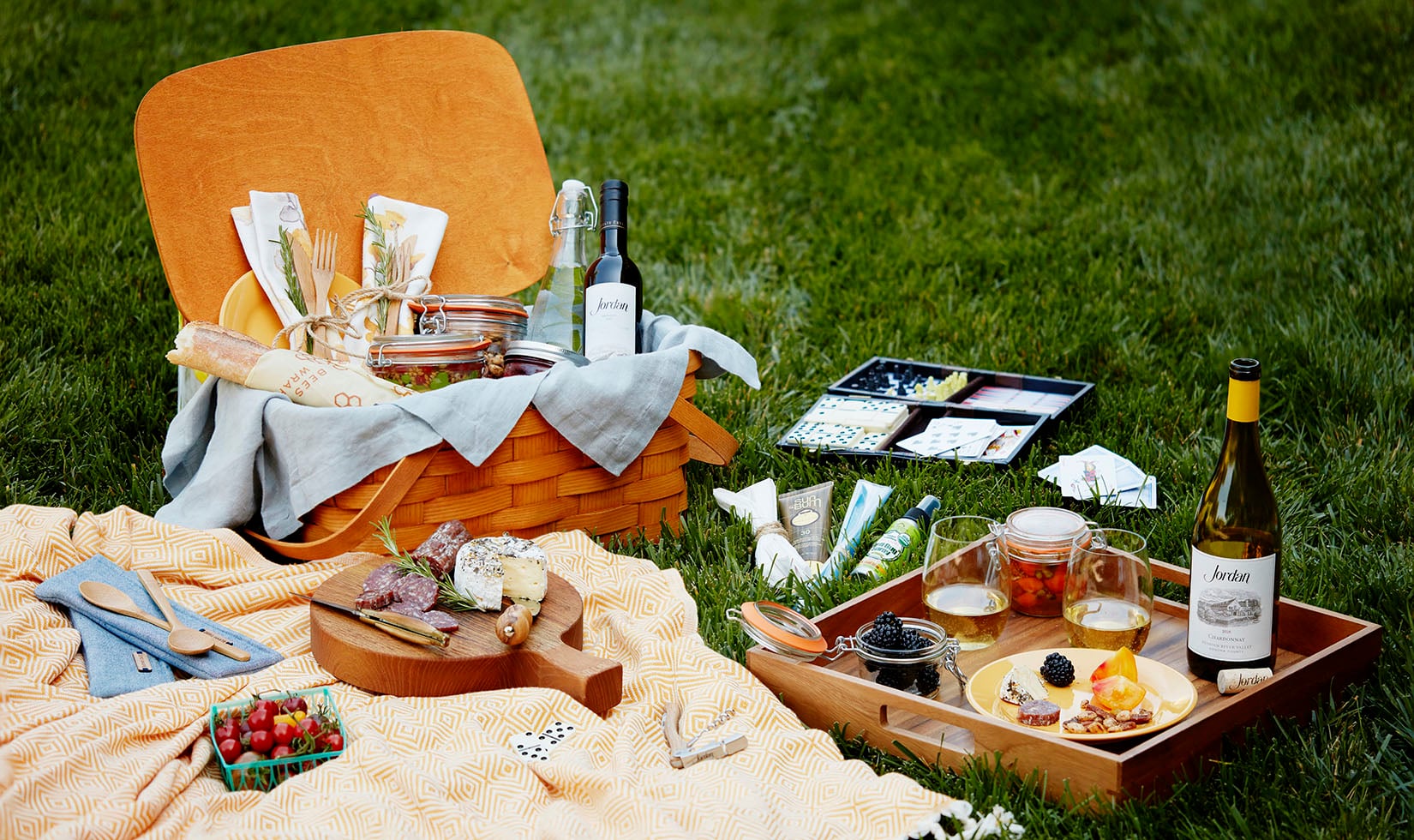 The ultimate picnic basket on the lawn with cheese, charcuterie, games and Jordan Chardonnay.