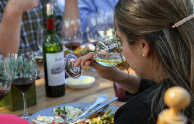woman holding a glass of chardonnay to her nose at the lunch table