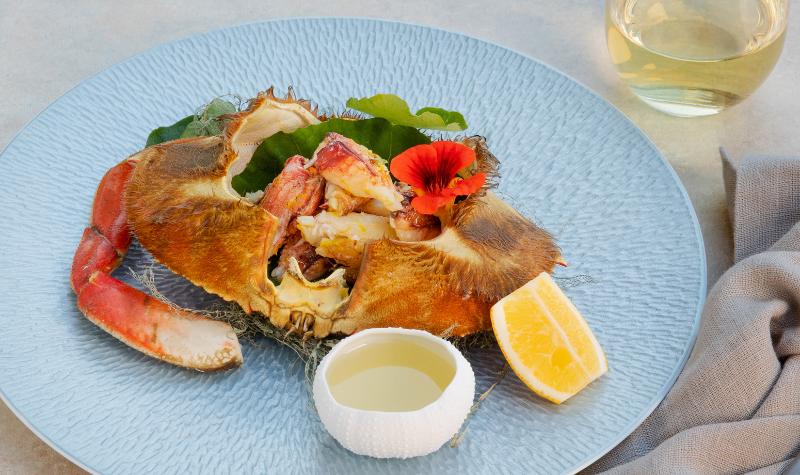 Best Dungeness Crab Recipes Dungeness crab with chardonnay drawn butter on blue plate with Jordan chardonnay glass