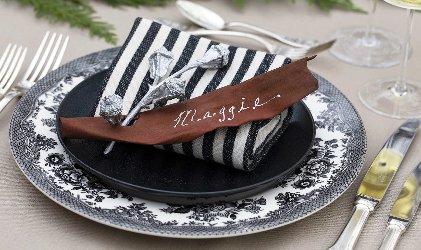 Elegant Christmas Table Setting Ideas Jingle Bells Eucalyptus Pods Place Setting on black and white plates