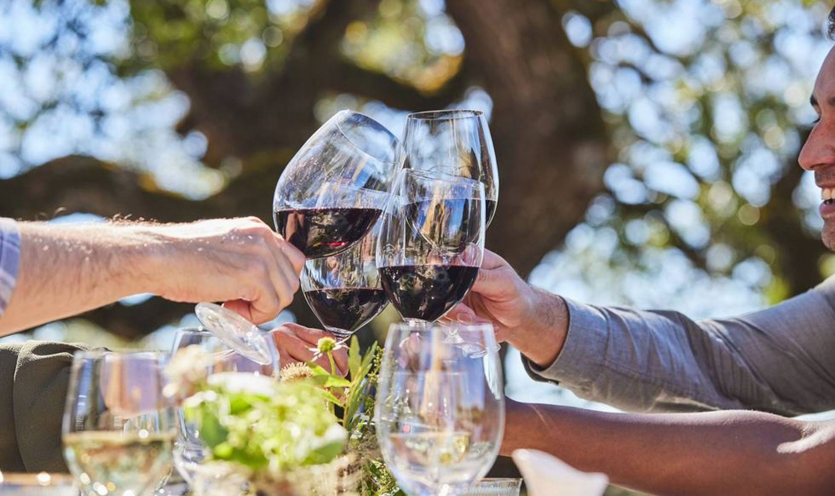 Group cheers with glasses of cabernet sauvignon over a table on the terrace at the Jordan Chateau.
