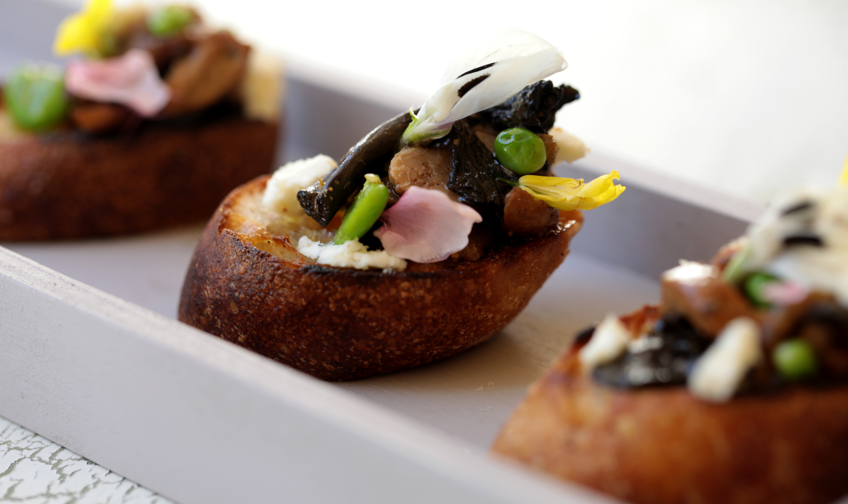 Top Sophisticated Appetizers mushroom and pea shoots on a toasted crostini bread