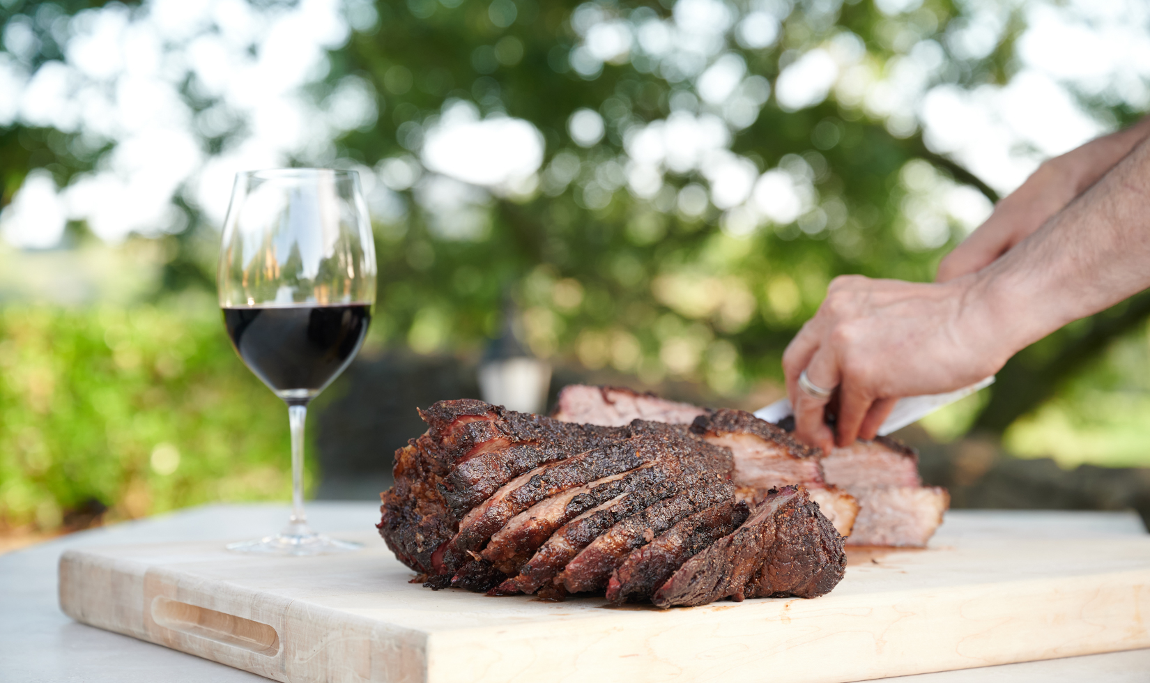 Wine Pairing with BBQ person slicing the meat in the table with red wine glass