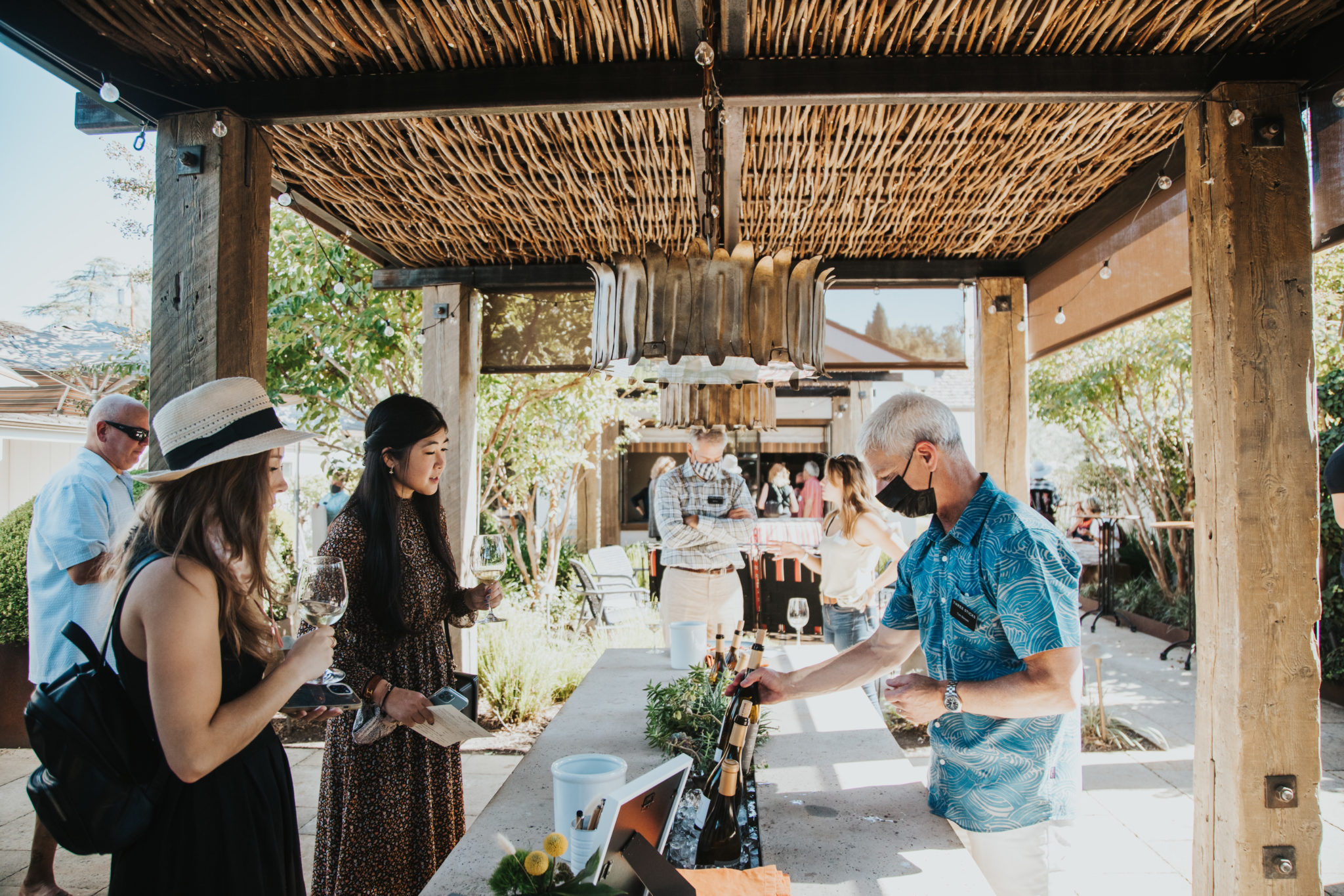 Guests are poured wines in front of outdoor tasting bar on terrace
