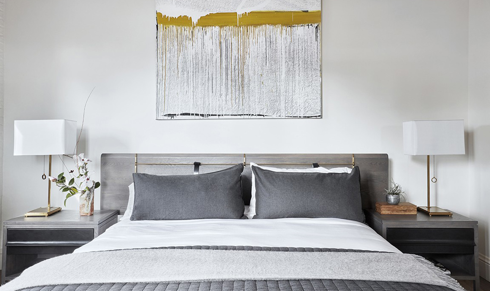 Modern bedroom with monochrome decor and abstract artwork.