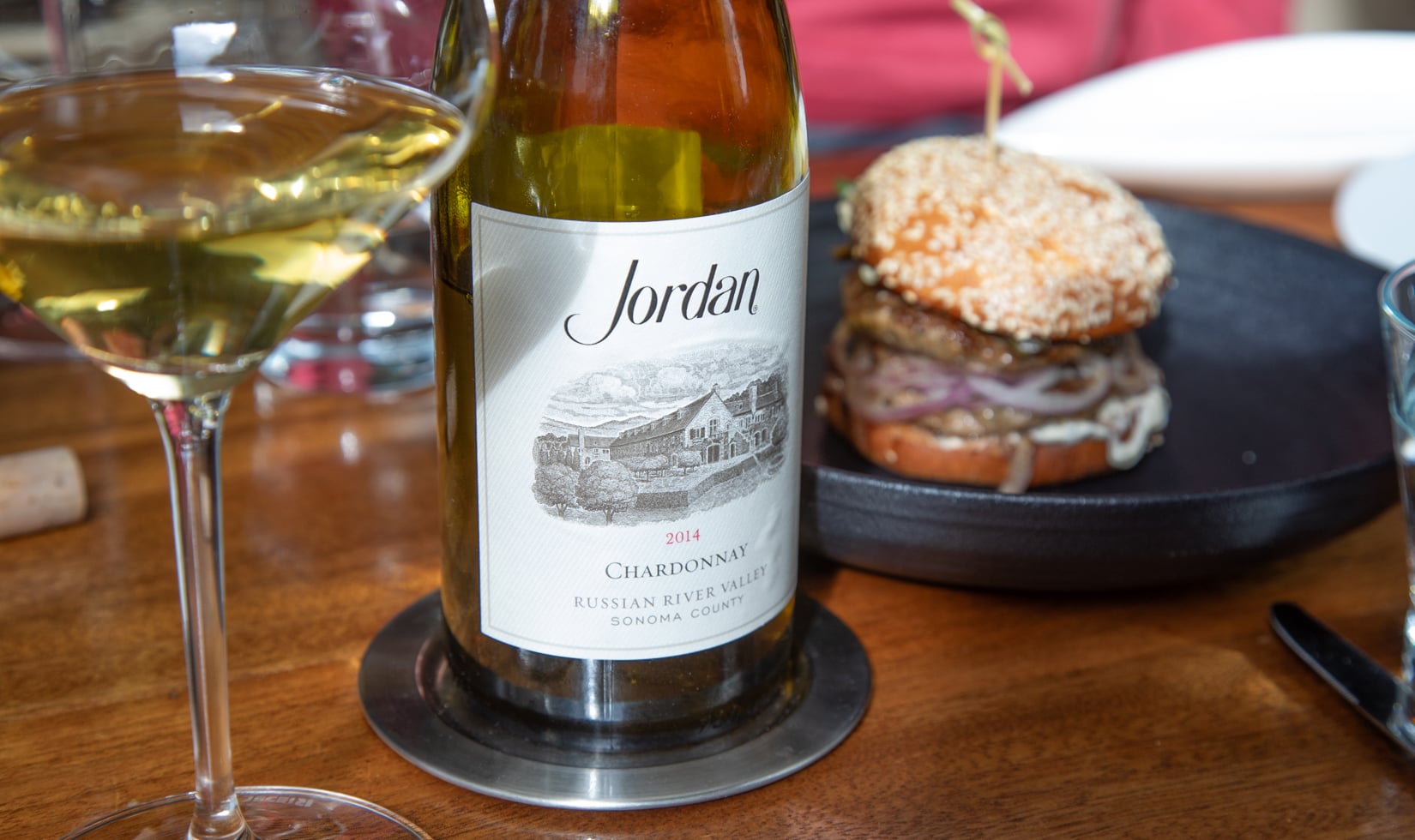 How to Read a Wine List Image bottle of chardonnay with wine glass, wine list menu and burger on a plate in the background