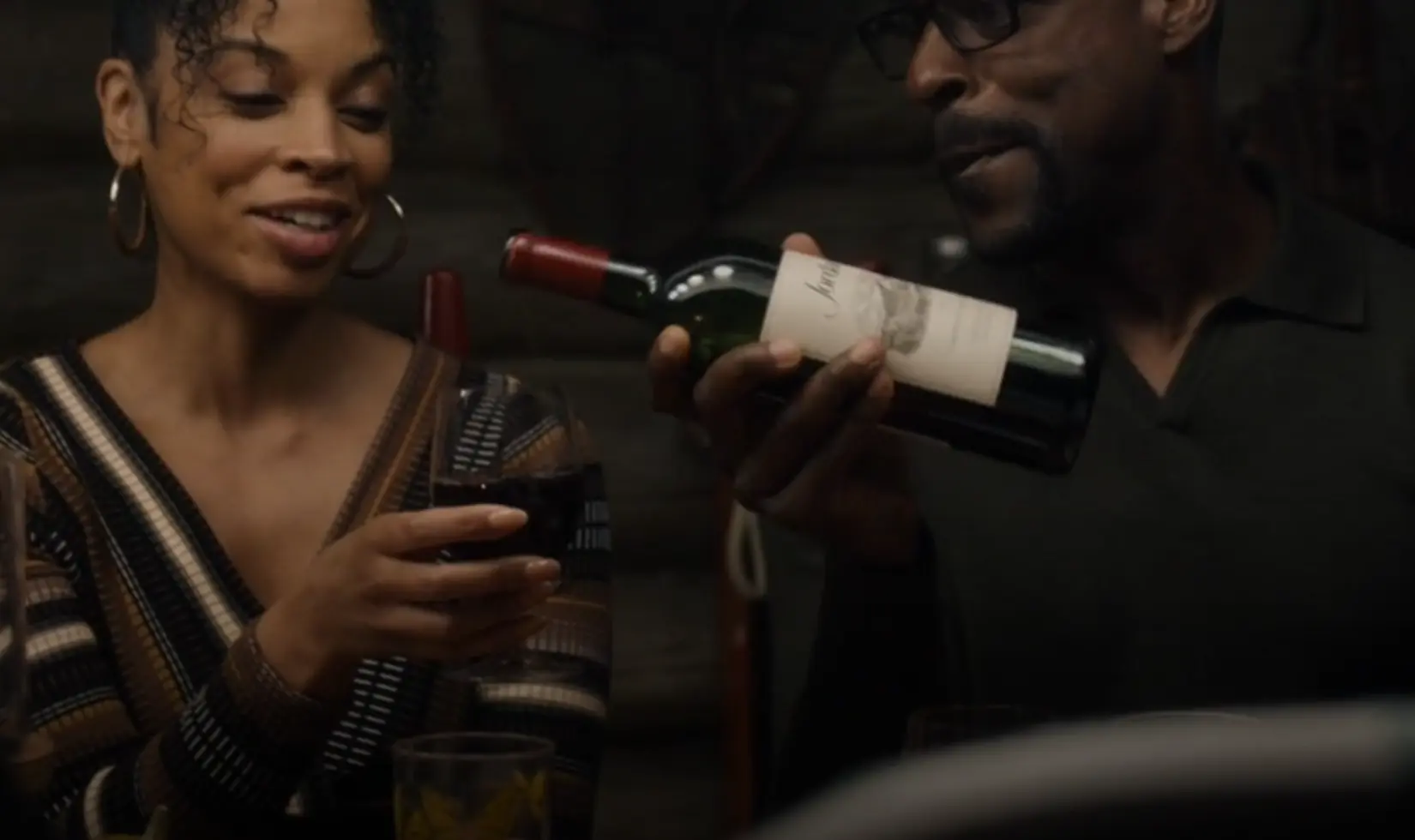 A man pouring red wine to a womans' wine glass